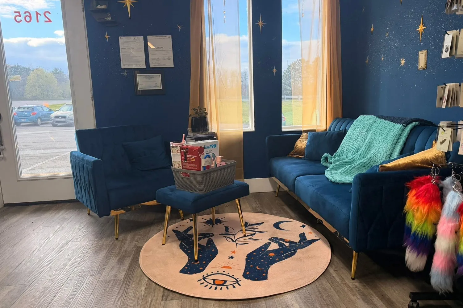 Seraph & Stardust waiting area with navy walls dotted with gold stars, a celestial moon-phase rug, blue velvet seating and rainbow accents