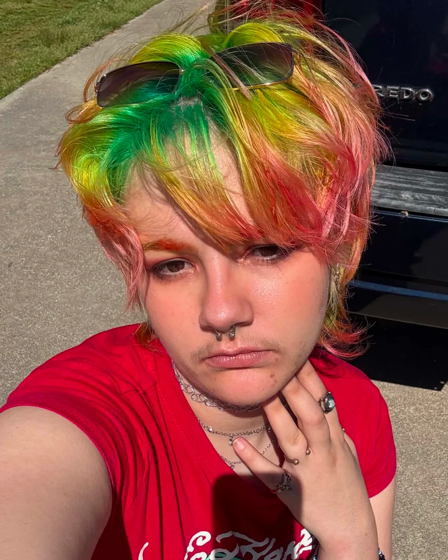 Icarus, hairstylist and colorist, with a green to orange to pink rainbow shag cut and sunglasses pushed up on top